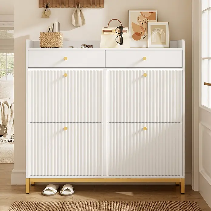 SONNENH Schuhschrank - Weiß - Weißer Schuhschrank mit geriffelten Türen, goldenen Griffen und Sockel im Eingangsbereich, dekoriert mit Accessoires.