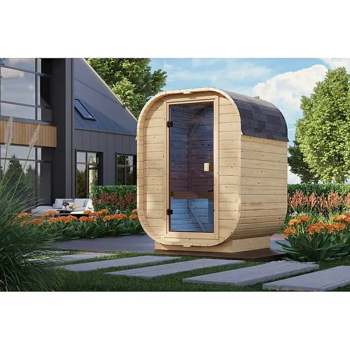 Karibu Saunahaus Sam - Mit Ofen, L x B x H: 140 x 158 x 205 cm - Hölzerne Fasssauna mit Glastür und Schindeldach, auf einer Terrasse neben einem modernen Haus.