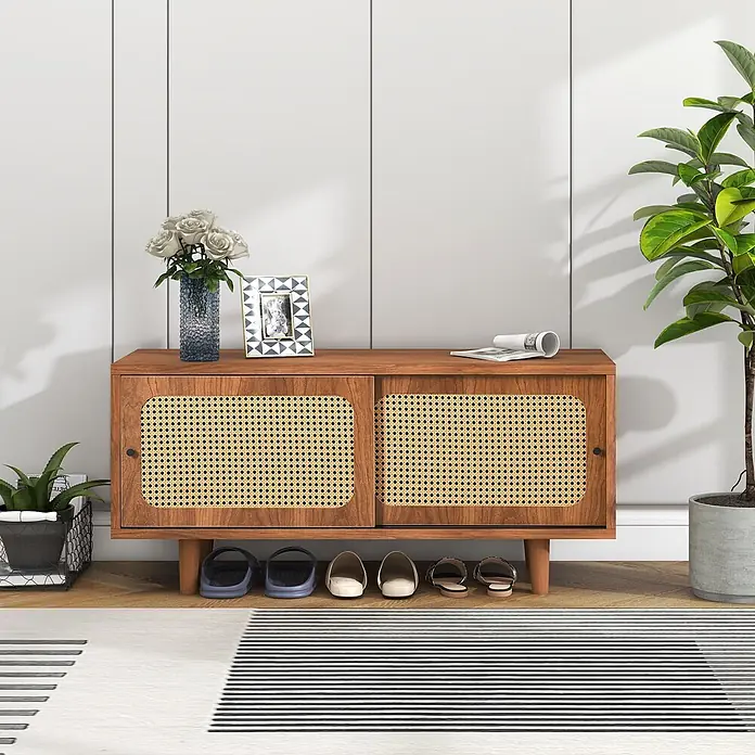 SONNENH Schuhschrank - Walnussoptik - Ein brauner Holzschuhschrank im Mid-Century-Modern-Stil mit Schiebetüren aus Rattan, Schuhe darunter, als Flurkonsole inszeniert.