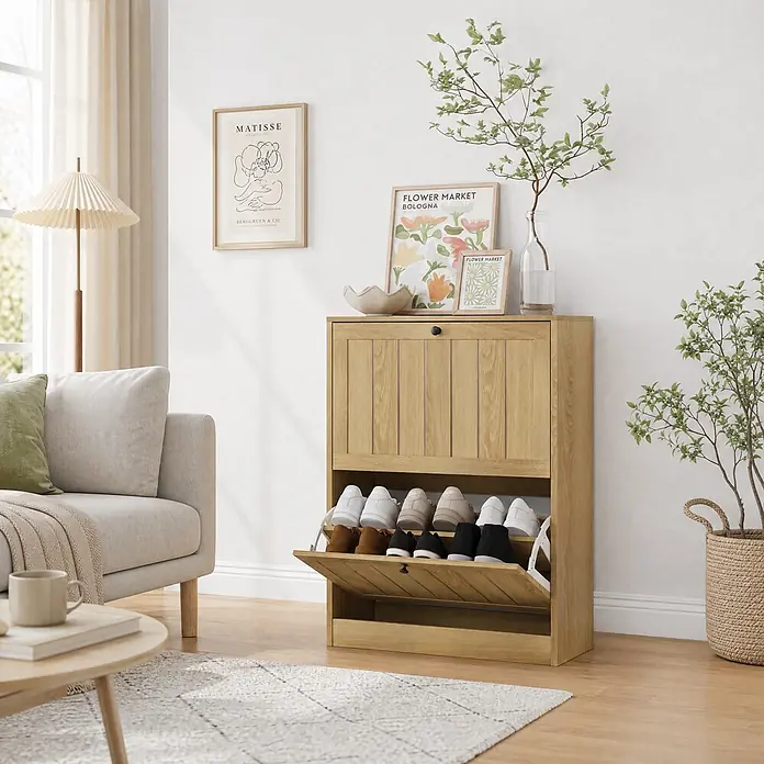 SONNENH Schuhschrank - Eichenoptik - Heller Holzschuhschrank mit zwei Kippfächern, das untere geöffnet mit Schuhen, in einem neutralen Raum.