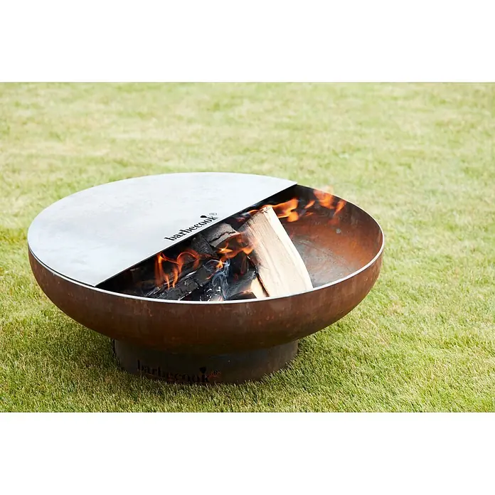 Barbecook Grillplatte Plancha - L x B: 62 x 31 cm, Kohlenstoffstahl - Rostfarbene Barbecook Feuerschale mit silberner Grillplatte über brennendem Holz.