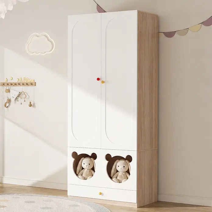 SONNENH Kleiderschrank - Weiß/Holzoptik - Weißer und holzfarbener Kinderschrank mit zwei Türen, bunten Knöpfen und zwei bärenkopfförmigen offenen Fächern mit Stoffhasen, in einem Kinderzimmer.