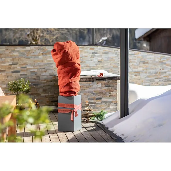 Windhager Jute-Gewebematte - Rot, L x B: 1 x 4 m, 200 g/m² - Grauer Pflanzkübel mit roter Stoff-Winterabdeckung und Zierband auf verschneiter Terrasse.