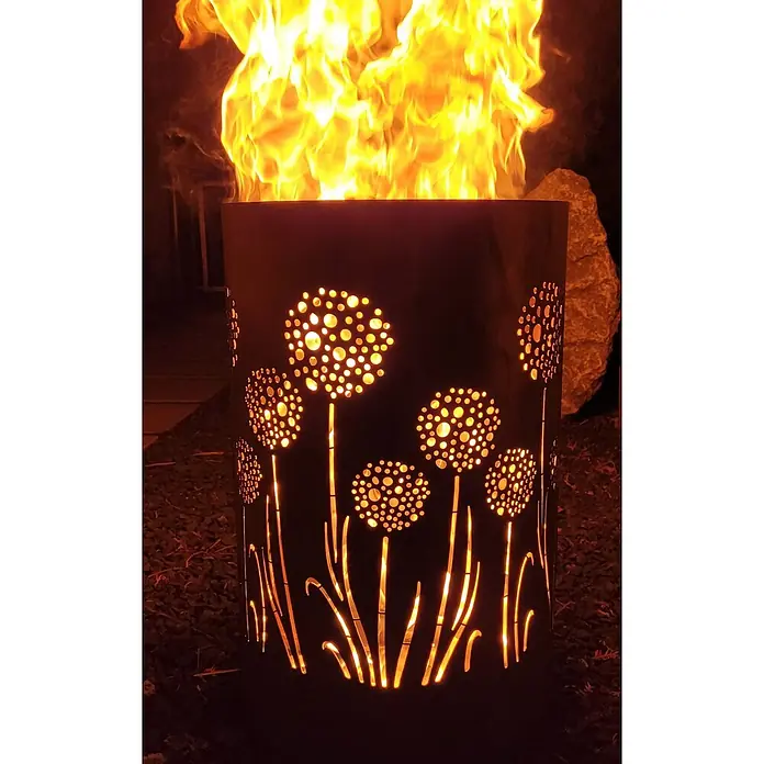 TiKo-Design® Feuertonne Pusteblume Ø 40 cm – Feuerstelle für Garten -  - Dunkle Metall-Feuerschale mit löwenzahnähnlichen Ausstanzungen, nachts hell orange vom Feuer leuchtend.