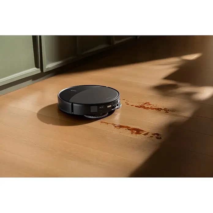 Roborock Saugwischroboter Saros 20X - Saugkraft: 36.000 Pa, Akkulaufzeit: 200 min, Fassungsvermögen Roboter: 259 ml - Schwarzer Saugroboter auf hellem Holzboden, neben einer braunen Verschüttung, seine Reinigungsfunktion zeigend.