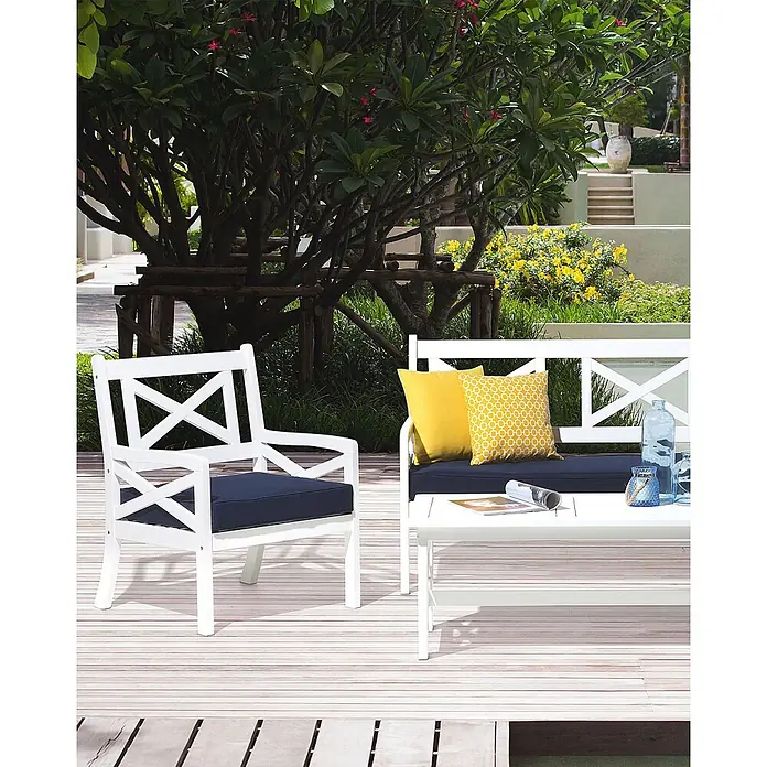 Beliani Gartenstuhl BALTIC - 1 Stk., Akazienholz, Weiß, B x T x H: 65 x 69 x 90 cm - Weißes Gartenmöbel-Set mit navyfarbenen Polstern und gelben Kissen auf einer Holzterrasse.