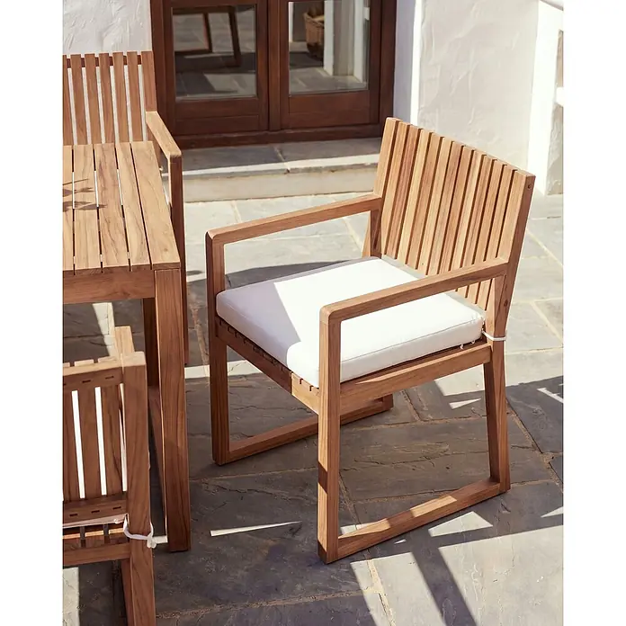 Beliani Gartenstuhl-Set SASSARI II PREMIUM - 4 Stk., zertifiziertes Akazienholz, Braun, B x T x H: 54 x 59 x 80 cm - Teakholz-Terrassenstuhl mit weißem Kissen, Teil einer Outdoor-Essgruppe auf Steinplatten.