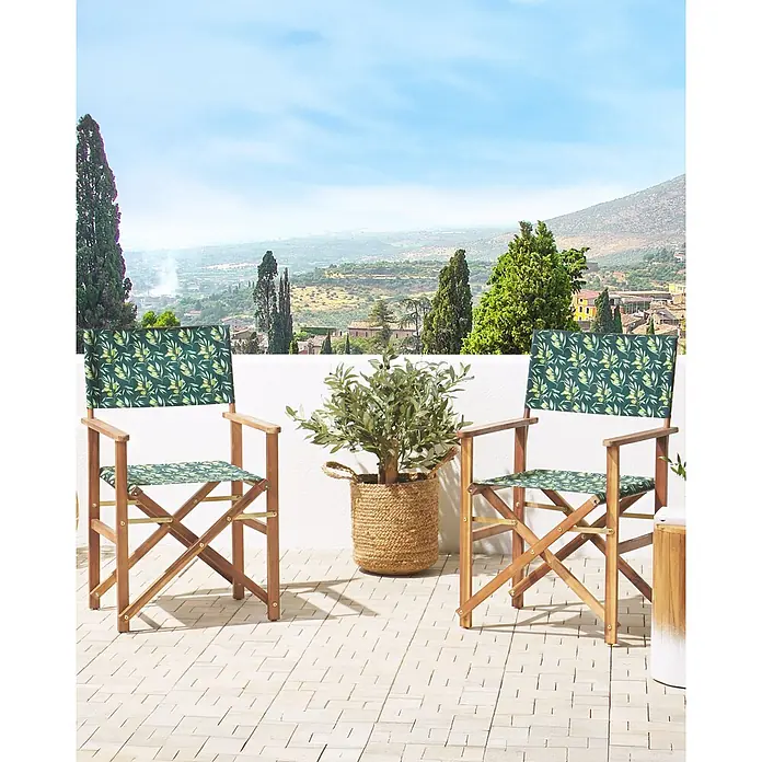 6er-Set Gartenstuhl CINE in Grün/Weiß/Braun -  - Zwei hölzerne Regiestühle mit dunkelgrünem Olivenmuster-Stoff an Sitzflächen und Rückenlehnen, auf einer Terrasse mit Panoramablick.