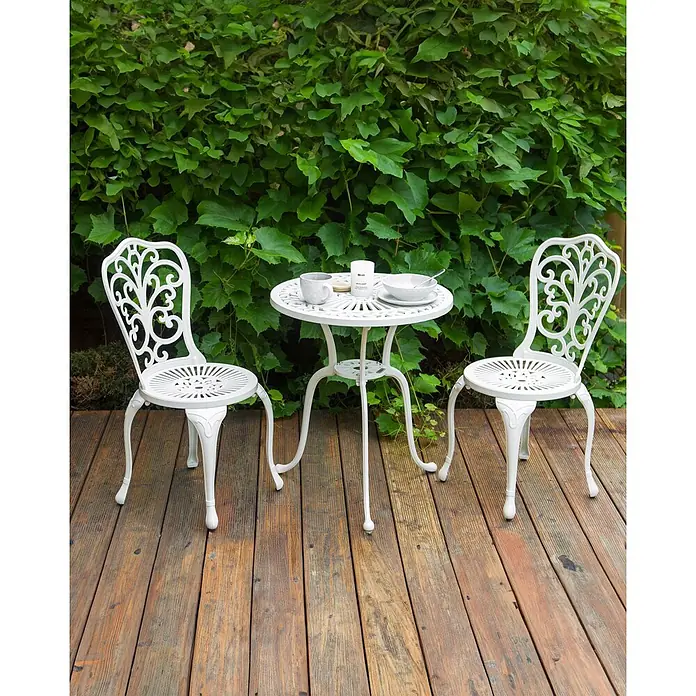 Beliani Gartenstuhl-Set TRIORA - 2 Stk., Aluminium, Weiß, B x T x H: 50 x 50 x 88 cm - Weißes, ornamentales Gusseisen-Bistro-Set mit zwei Stühlen und einem Tisch auf einer Holzterrasse.