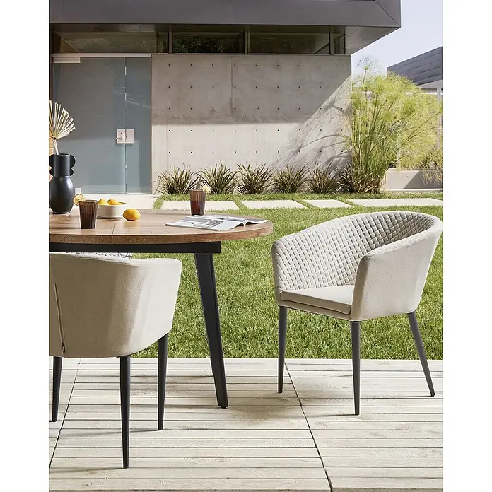 2er-Set Gartenstuhl CURGOS in Beige/Schwarz -  - Zwei hellbeige Stoff-Esszimmerstühle mit dunklen Beinen und ein runder Holztisch auf einer Terrasse im Freien.