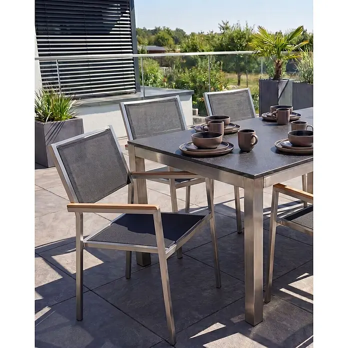 6er-Set Gartenstuhl GROSSETO in Schwarz/Silber/Braun -  - Gartenmöbel-Set mit dunklem Steintisch und Stühlen aus Edelstahl und dunklem Netzstoff, auf einer Terrasse zum Essen gedeckt.