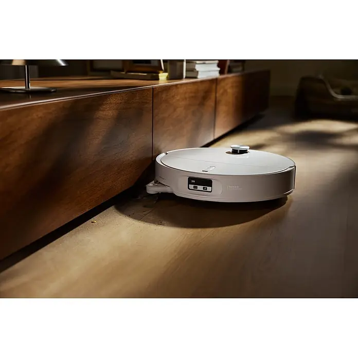 Roborock Saugwischroboter Qrevo Edge 2X - Saugkraft: 25.000 Pa, Akkulaufzeit: 188 min, Fassungsvermögen Roboter: 240 ml, Weiß - Ein weißer Saugroboter reinigt einen Holzboden neben einem Holzschrank, mit sichtbaren Krümeln auf dem Boden.