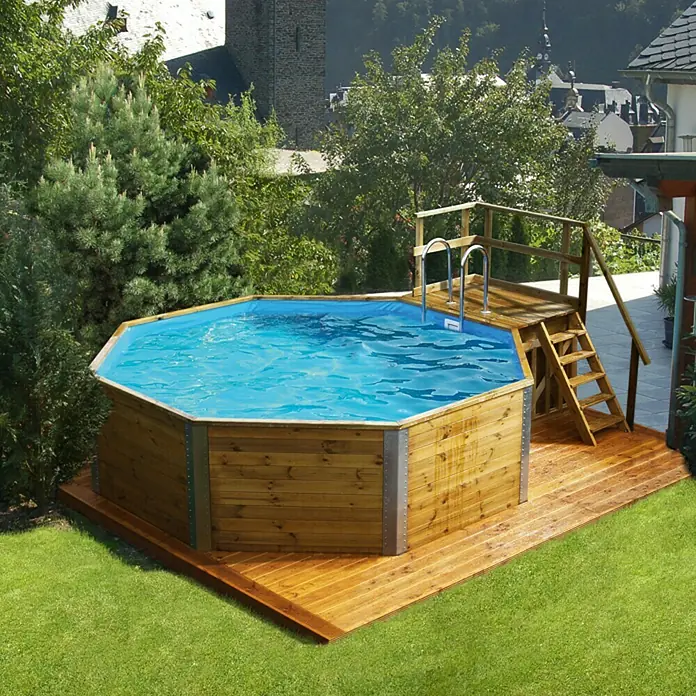 Weka Holz-Pool Acapulco I - L x B x H: 476 x 376 x 116 cm, 11.400 l - Ein achteckiger Holzpool mit einer Leiter und einer hölzernen Plattform im Garten. Der Pool ist mit klarem, blauem Wasser gefüllt.