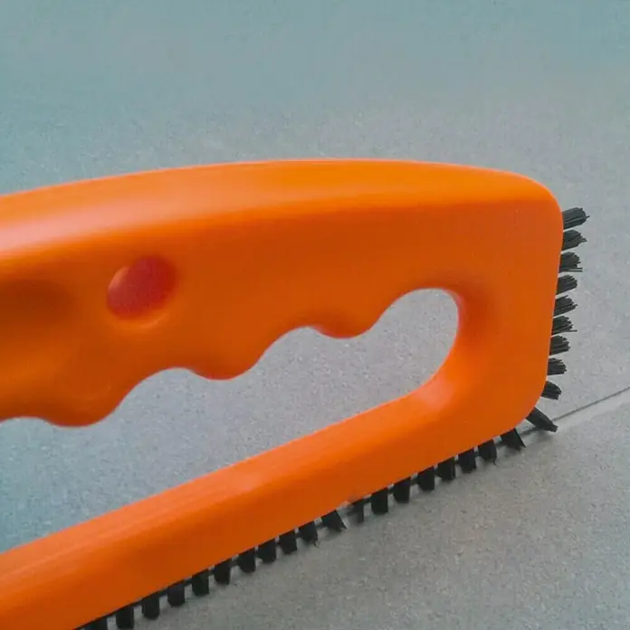 Patina-Fala Fugenbürste - Geeignet für: Zementfugen - Nahaufnahme einer Fugenbürste mit orangefarbenem Griff und schwarzen Borsten zum Reinigen von Fliesenfugen.