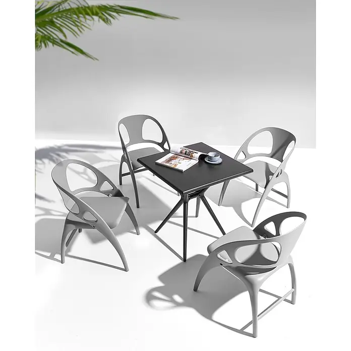 4er-Set Gartenstuhl NEMI in Grau -  - Ein dunkelgrauer quadratischer Tisch mit vier hellgrauen Stühlen, im Freien arrangiert mit Magazin und Tasse auf dem Tisch.