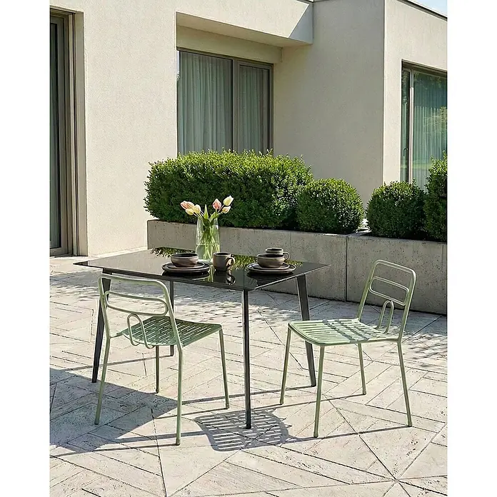 2er-Set Gartenstuhl AGEROLA in Grün -  - Salbeigrüne Outdoor-Stühle und ein schwarzer Esstisch auf einer Terrasse, gedeckt mit Geschirr und Tulpen.