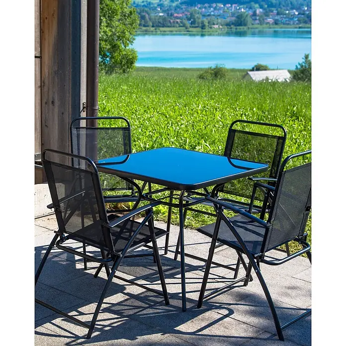 4er-Set Gartenstuhl LIVO in Schwarz -  - Eine schwarze Gartensitzgruppe mit Glastisch und vier Netzstühlen steht auf einer Terrasse vor See- und Wiesenlandschaft.