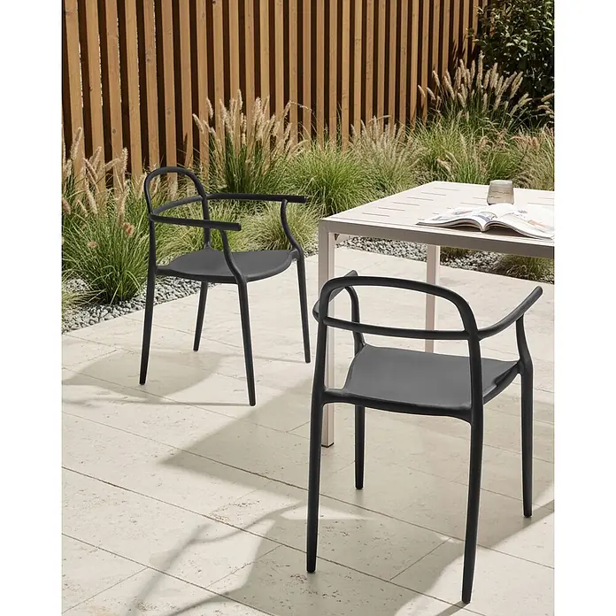 2er-Set Gartenstuhl VIDOR in Schwarz -  - Schwarzer moderner Outdoor-Stuhl mit geschwungenen Armlehnen, auf einer Terrasse mit Tisch und Pflanzen.