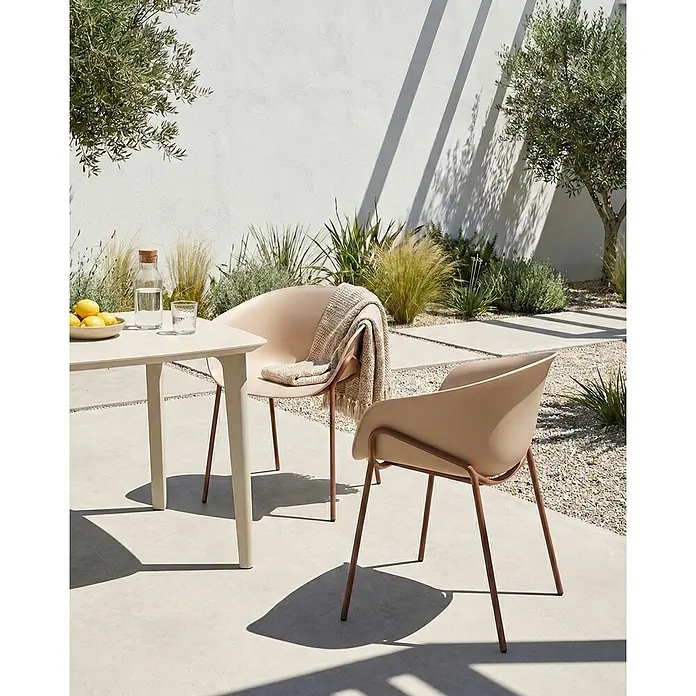 2er-Set Esszimmerstuhl METEORA in Beige/Braun -  - Beige Outdoor-Stühle und ein Tisch mit bronzefarbenen Beinen auf einer sonnigen Terrasse. Ein Stuhl hat eine Decke; der Tisch hat Zitronen und Wasser.