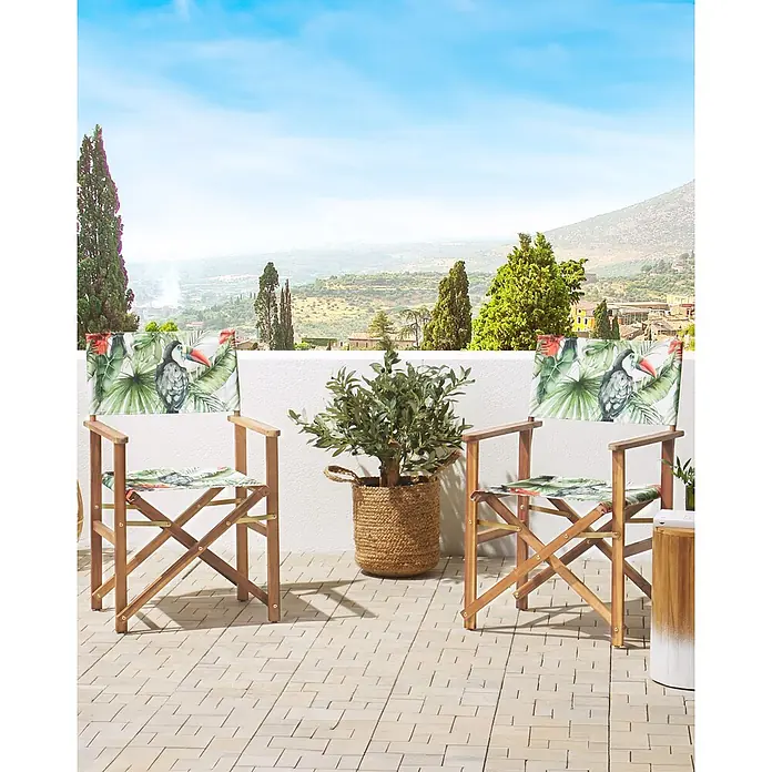 6er-Set Gartenstuhl CINE in Grün/Bunt/Grün -  - Zwei hölzerne Regiestühle mit tropischem Tukan- und Blattmusterstoff auf einem Balkon mit Landschaftsblick.