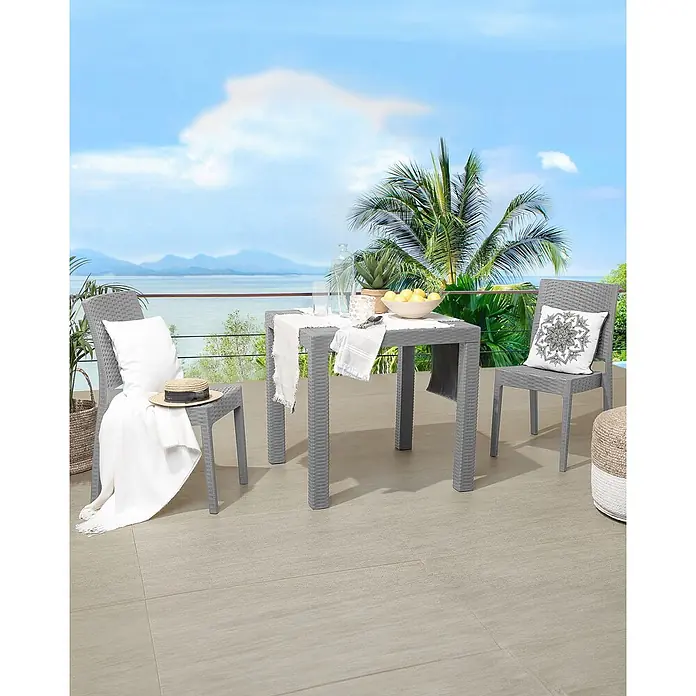 2er-Set Gartenstuhl FOSSANO in Grau -  - Graues Outdoor-Essgruppe aus Kunststoff im Rattan-Stil auf einer Terrasse mit Meerblick, bestehend aus Tisch und zwei Stühlen.