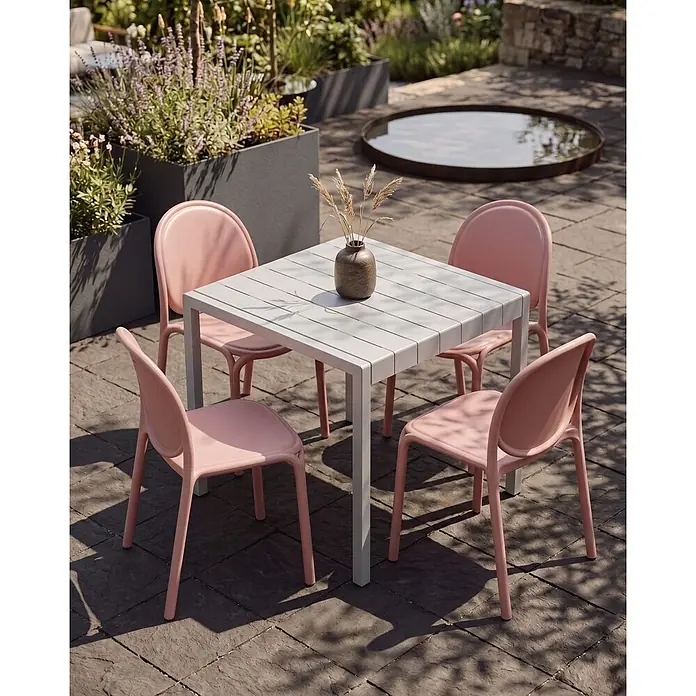 4er-Set Esszimmerstuhl BRUGNELLO in Rosa -  - Outdoor-Essgruppe: ein hellgrauer Lamellentisch und vier rosa Stühle auf einer Terrasse.