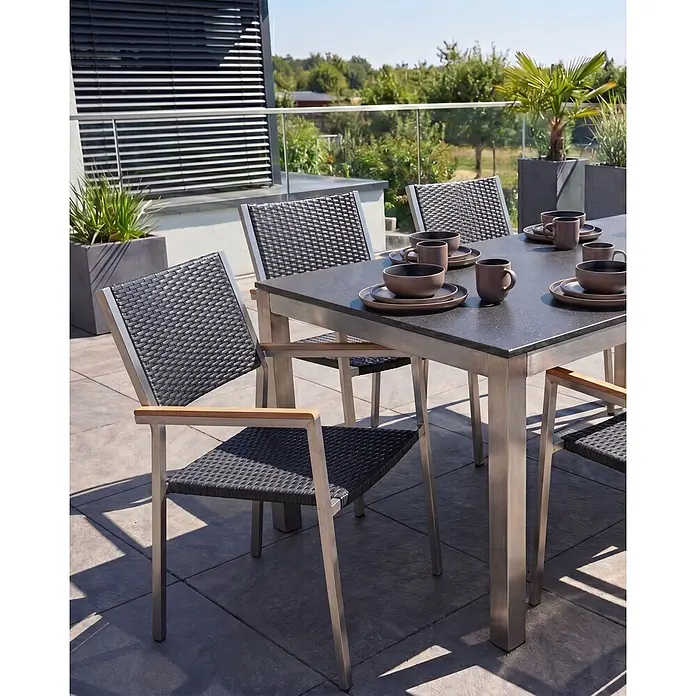 6er-Set Gartenstuhl GROSSETO in Schwarz/Silber -  - Eine Outdoor-Essgruppe mit dunklem, gesprenkeltem Tisch und Stühlen mit dunklen Geflechtsitzen, Metallrahmen und Holzarmlehnen auf einer Terrasse.
