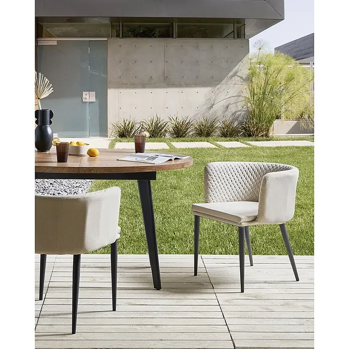 2er-Set Gartenstuhl LIMASSON in Beige/Schwarz -  - Beige gepolsterte Esszimmerstühle und Holztisch auf einer Terrasse für Mahlzeiten im Freien.