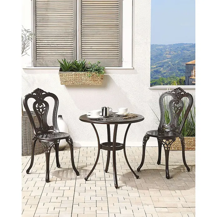 Beliani Gartenstuhl-Set BOVINO - 2 Stk., Aluminium, Braun, B x T x H: 43 x 53 x 90 cm - Dunkelbraunes Outdoor-Bistro-Set aus Aluminiumguss mit rundem Tisch und zwei verzierten Stühlen auf einer Terrasse.
