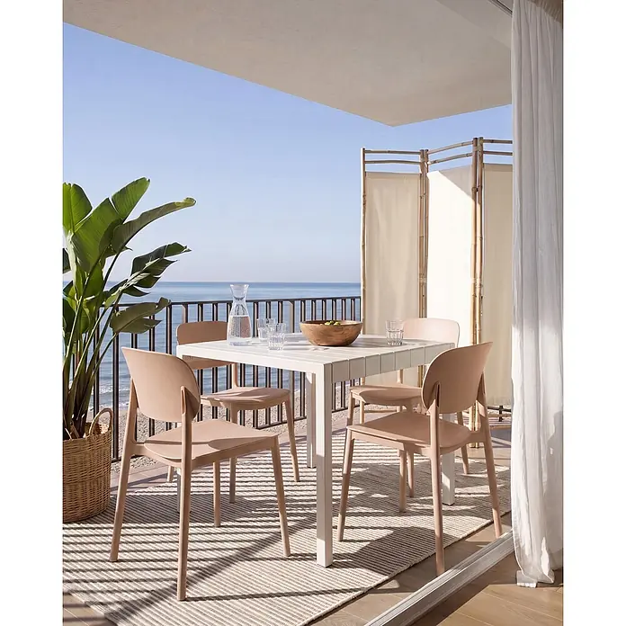 4er-Set Gartenstuhl TUPIZA in Beige -  - Weißer Gartentisch mit hellbraunen Stühlen auf einem Balkon mit Meerblick.