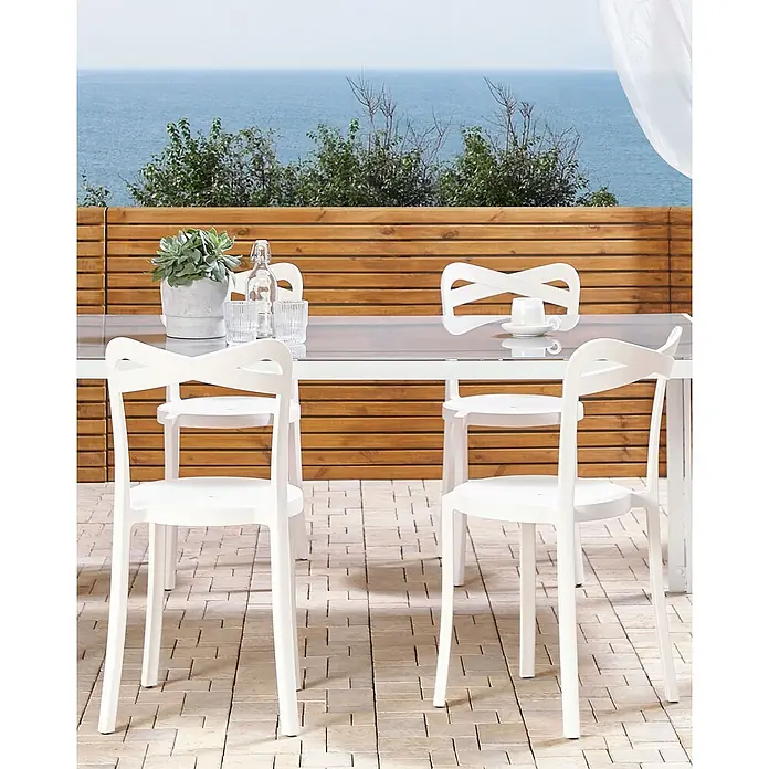 4er-Set Gartenstuhl CAMOGLI in Weiß -  - Weißes Outdoor-Essset mit modernen Stühlen und Tisch auf einer Terrasse mit Meerblick.