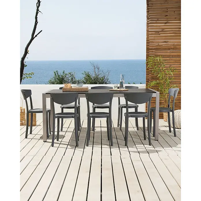 8er-Set Esszimmerstuhl VIESTE in Grau -  - Outdoor-Essgarnitur: dunkelgraue Stühle, dunkler Tisch auf heller Terrasse mit Meerblick, bereit zur Nutzung.