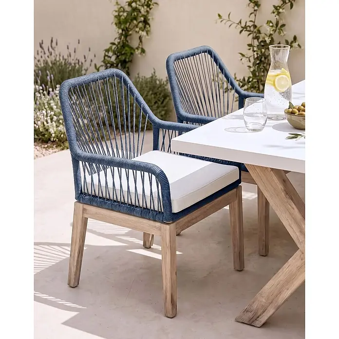 Beliani Gartenstuhl-Set OLBIA - 2 Stk., Akazienholz, Blau, B x T x H: 64 x 71 x 89 cm - Zwei blaue Outdoor-Esszimmerstühle aus geflochtenem Seil mit hellen Holzbeinen und weißen Kissen, an einem Tisch.