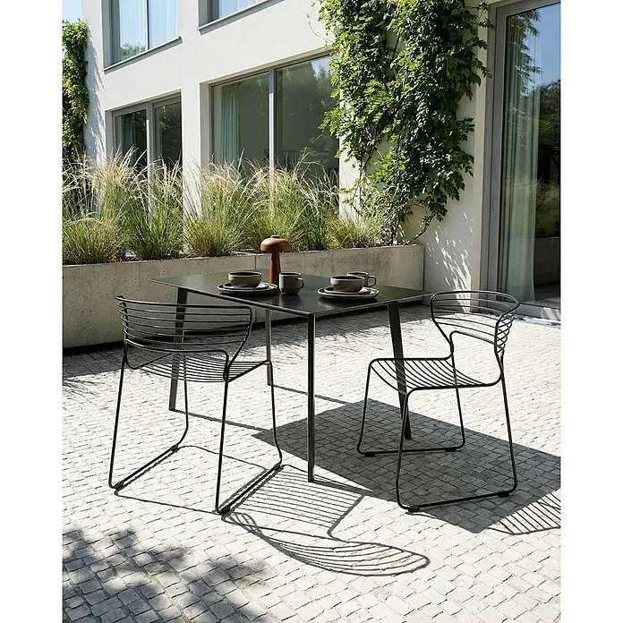 2er-Set Gartenstuhl PISTOIA in Schwarz -  - Schwarzes Outdoor-Esszimmer-Set aus Metall mit einem quadratischen Tisch und zwei Drahtstühlen auf einer gepflasterten Terrasse, mit Geschirr gedeckt.