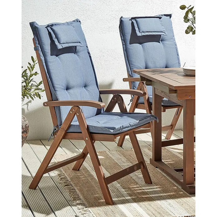 2er-Set Gartenstuhl AMANTEA in Braun/Blau -  - Klappbares Outdoor-Essgruppe aus Holz mit blauen Kissen auf einer Terrasse mit Teppich.