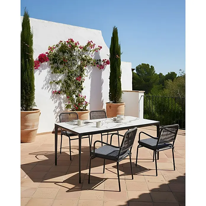 8er-Set Gartenstuhl TACENO in Grau -  - Essgruppe für den Außenbereich mit weißem Tisch und dunklen Stühlen auf einer sonnigen Terrasse.