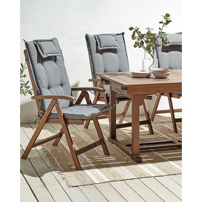 6er-Set Gartenstuhl AMANTEA in Braun/Grau -  - Outdoor-Essgruppe aus Holz mit Stühlen und weichen grauen Kissen auf einer Terrasse.