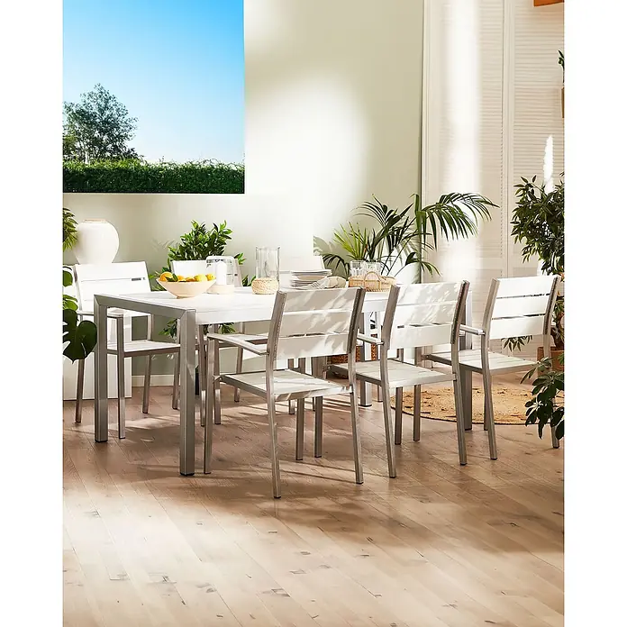 6er-Set Gartenstuhl VERNIO in Weiß/Silber -  - Weißer Lamellen-Esstisch und Stühle mit silbernen Gestellen, für eine Mahlzeit in einem hellen, pflanzenreichen Raum arrangiert.