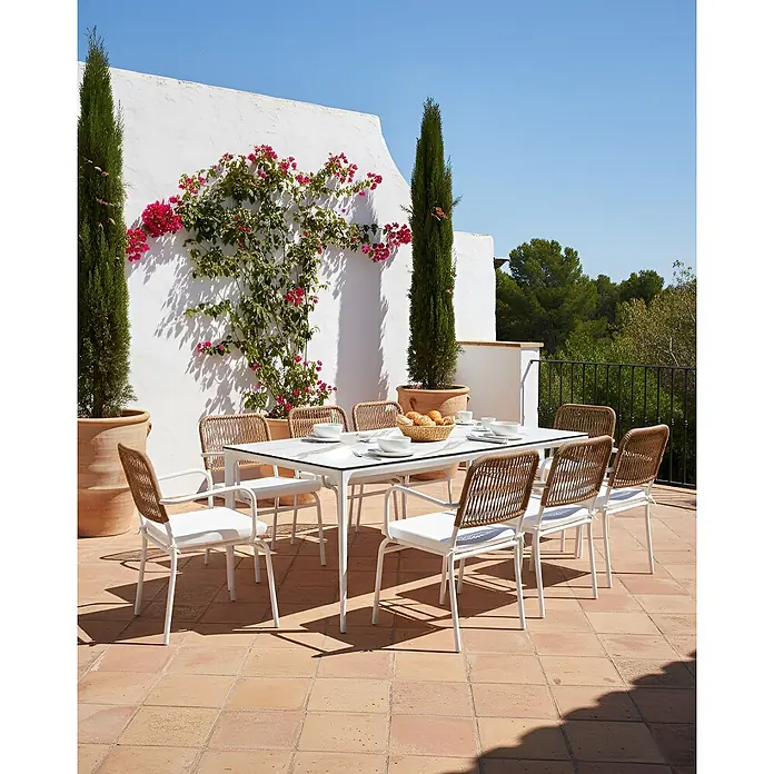 16er-Set Gartenstuhl TACENO in Weiß/Braun -  - Weißer Gartentisch mit acht Stühlen mit Rattangeflecht und weißen Kissen, auf einer Terrasse platziert.