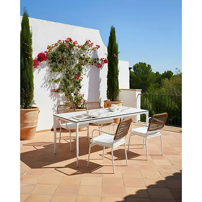 8er-Set Gartenstuhl TACENO in Weiß/Braun -  - Weißer Outdoor-Esstisch mit Marmoroptikplatte und vier Stühlen mit weißen Rahmen und geflochtenen braunen Rücken auf einer Sonnenterrasse.