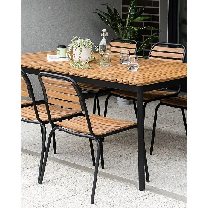 Beliani Gartenstuhl-Set VALLESE - 6 Stk., Akazienholz, Braun, B x T x H: 49 x 40 x 84 cm - Garten-Essgruppe mit Lattenholztisch und Stühlen, schwarzem Metallrahmen, auf einer Terrasse.