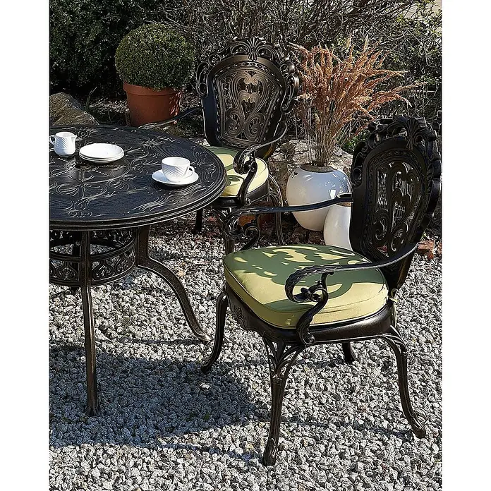Beliani Gartenstuhl-Set SAPRI - 2 Stk., Aluminium, Braun, B x T x H: 69 x 55 x 97 cm - Ein elegantes dunkles Metall-Terrassen-Essset mit kunstvollen Verzierungen und grünen Kissen auf einem Kiesweg.