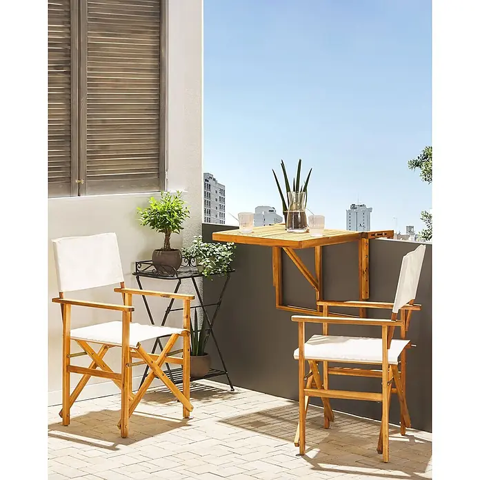 2er-Set Gartenstuhl CINE in Weiß/Braun -  - Klappbarer Balkontisch und zwei Regiestühle aus Holz mit weißen Stoffbezügen, auf einem sonnigen Balkon mit Pflanzen und Getränken.