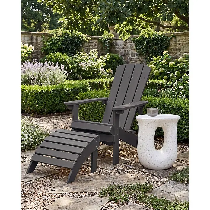 2-tlg Gartenstuhl ADIRONDACK in Grau -  - Dunkelgrauer Adirondack-Stuhl mit Hocker und weißem Beistelltisch im Garten.