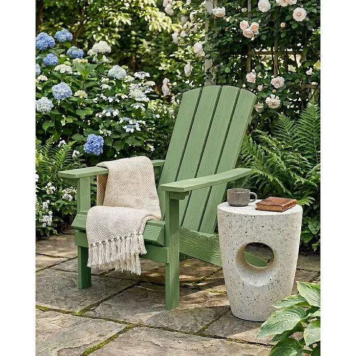 Gartenstuhl ADIRONDACK in Grün - (W) 75 x (H) 88 x - L - Ein grüner Adirondack-Stuhl mit Decke und ein weißer Beistelltisch mit Tasse und Buch, auf einer Steinterrasse im Garten.