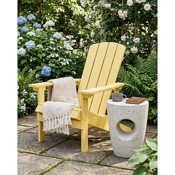Gartenstuhl ADIRONDACK in Gelb - (W) 75 x (H) 88 x - L - Gelber Adirondack-Stuhl mit gemusterter Decke, neben einem gesprenkelten Steintisch in einem Garten.