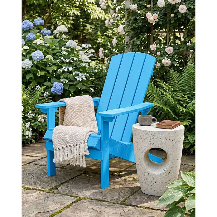 Gartenstuhl ADIRONDACK in Blau - (W) 75 x (H) 88 x - L - Leuchtend blauer Adirondack-Stuhl mit Decke und ein gesprenkelter Beistelltisch mit Tasse und Buch, im Garten.