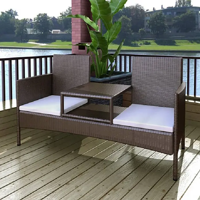 Furnicato Gartenbank 2-Sitzer PE-Rattan Braun mit Teetisch -  - Braunes Rattan 2-Sitzer-Loungesofa mit integriertem Tisch und weißen Kissen auf Holzterrasse am Wasser.
