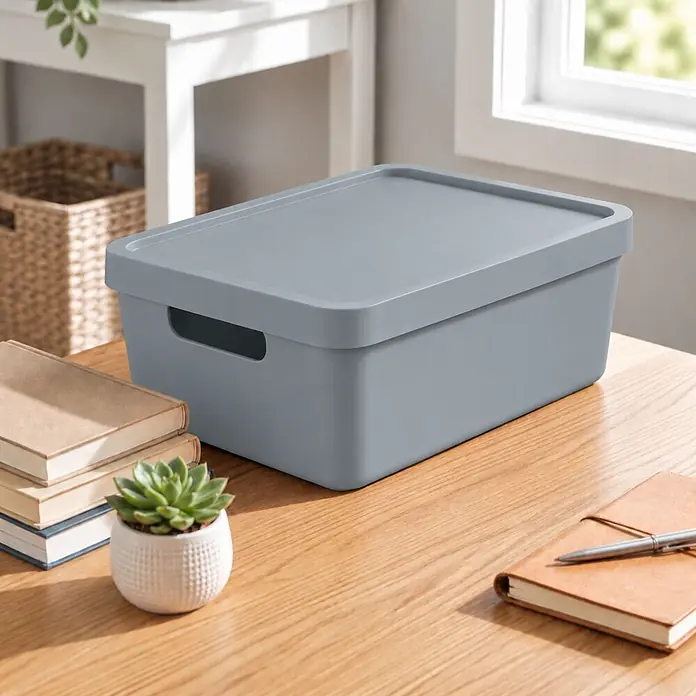 2er-Set 7,5 Liter in Grau mit Deckel – Stapelboxen, Lagerboxen -  - Graue Aufbewahrungsbox mit Deckel auf einem Holztisch, neben Büchern und einer Pflanze.
