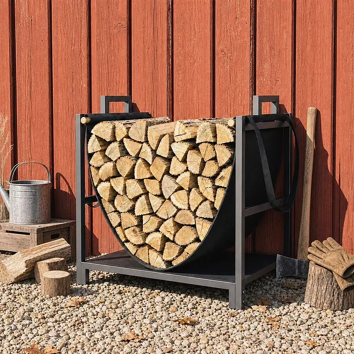 Outsunny Kaminholzregal - Metall, Schwarz - Schwarzes Metall-Kaminholzregal mit Stoffeinsatz, gefüllt mit Holzscheiten, vor roter Scheunenwand auf Kies.